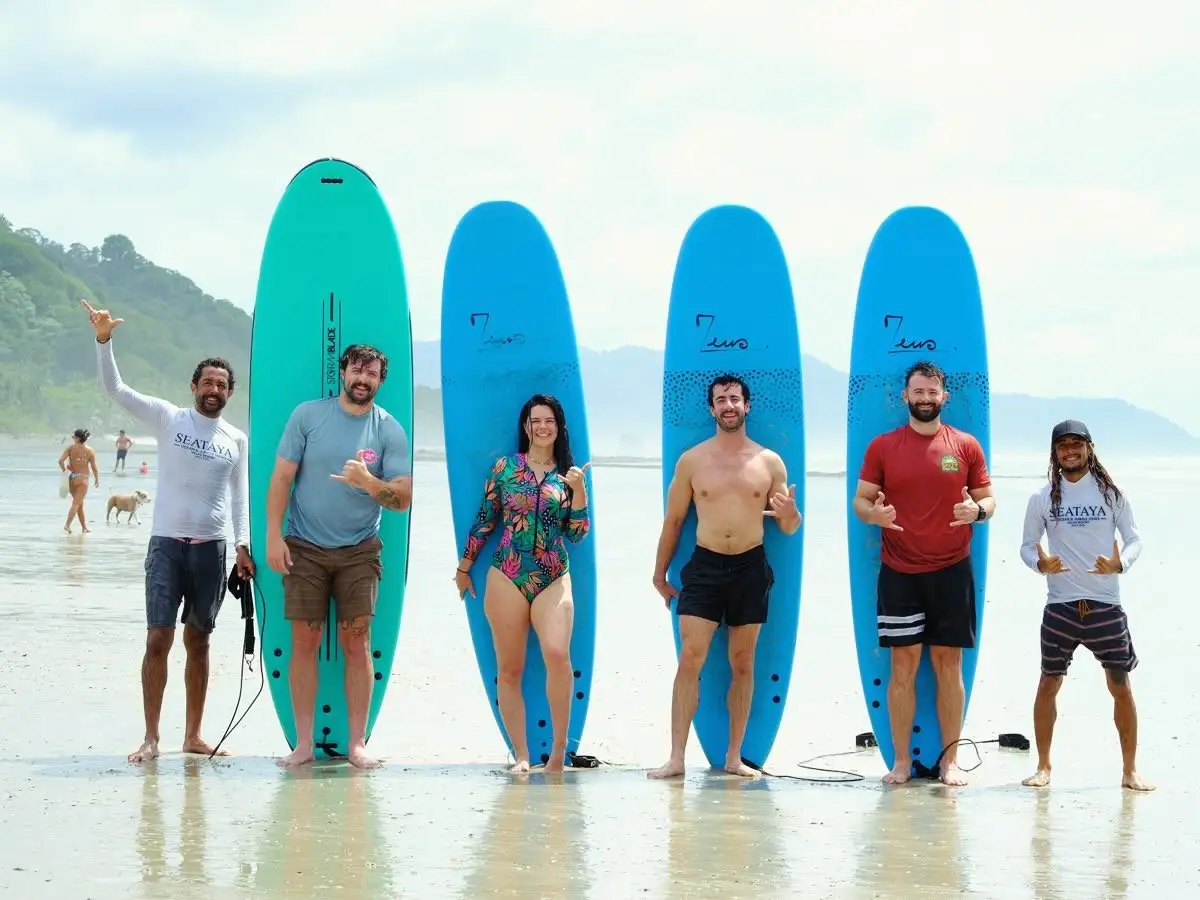 Smiling surf group with instructors and soft-top boards on the beach in Santa Teresa