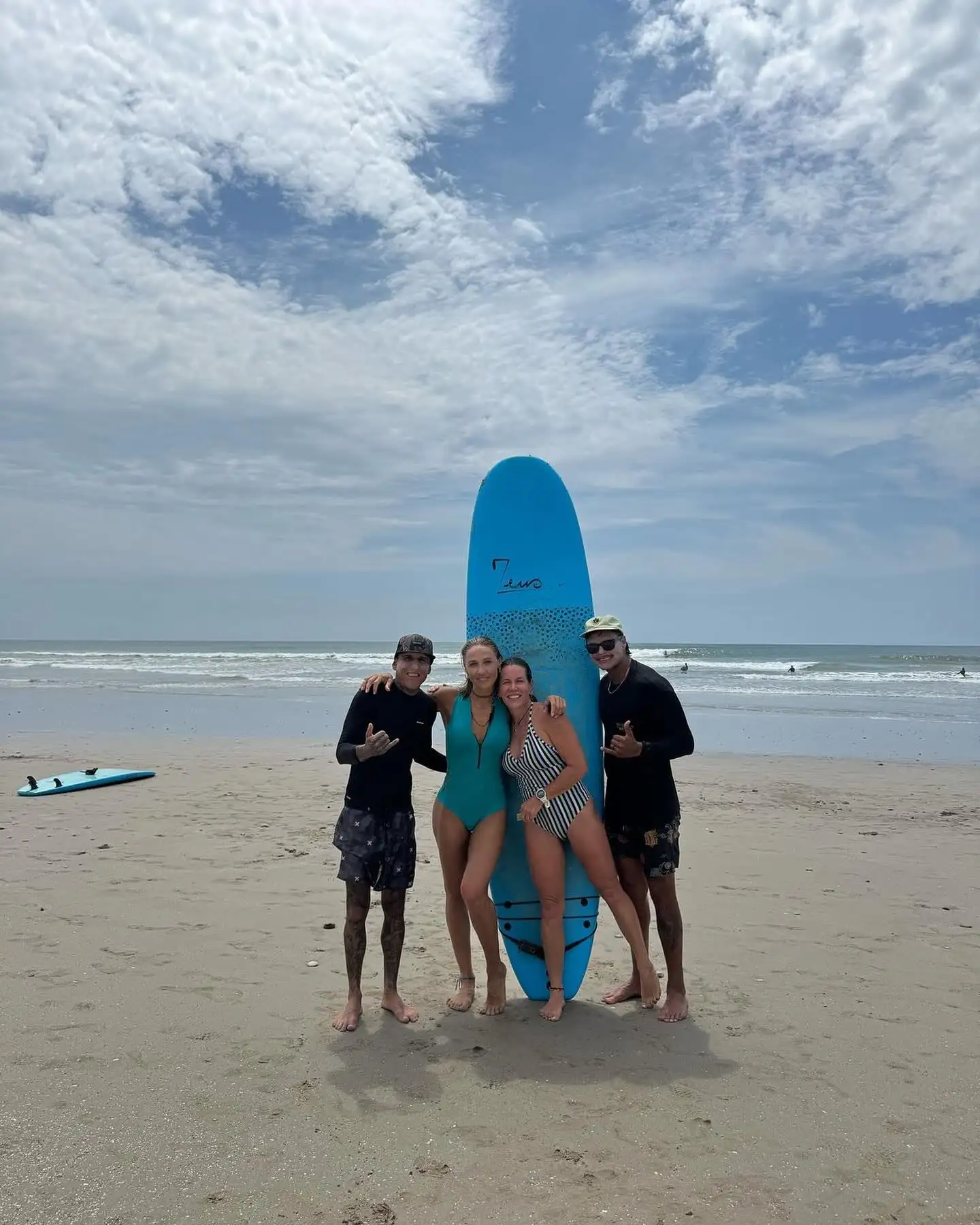 Happy students and their instructor with a surfboard after the lesson