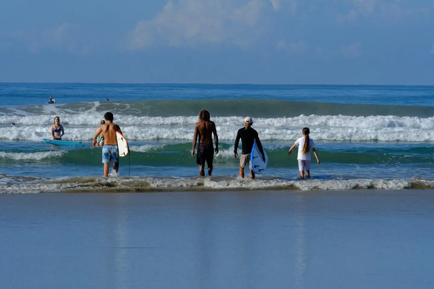 Surf students walking into the waves with their boards